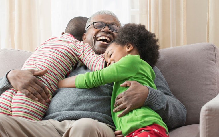 consulting case study vaccine Smiling man sitting on couch, hugging two grandchildren